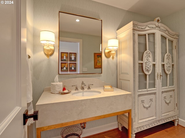 bathroom featuring wood finished floors, vanity, and wallpapered walls