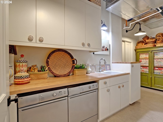 kitchen with butcher block counters, white dishwasher, a sink, and white cabinetry