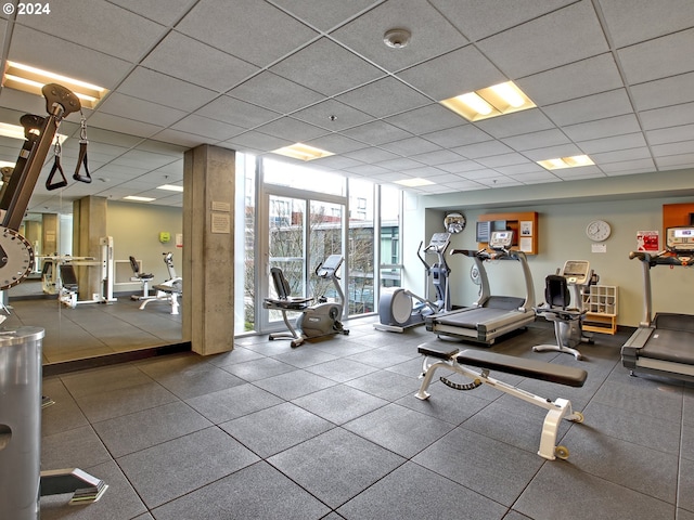 workout area featuring a drop ceiling and a wall of windows