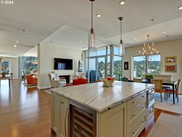 kitchen with a kitchen island, hardwood / wood-style floors, decorative light fixtures, wine cooler, and an inviting chandelier