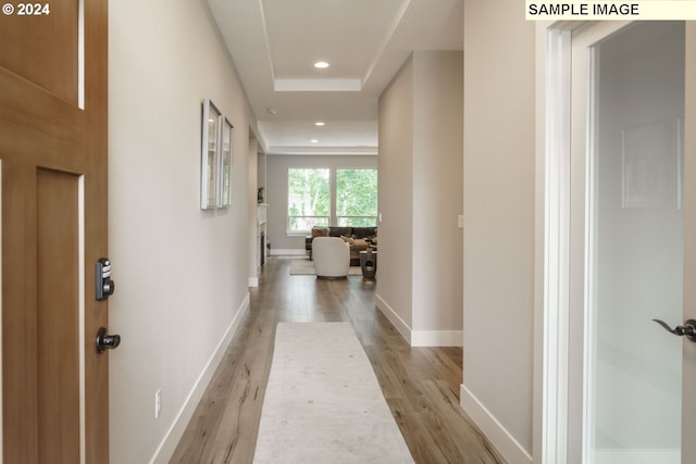 hall featuring a tray ceiling and light hardwood / wood-style flooring