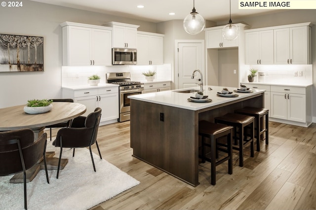 kitchen featuring backsplash, a kitchen island with sink, hanging light fixtures, sink, and appliances with stainless steel finishes