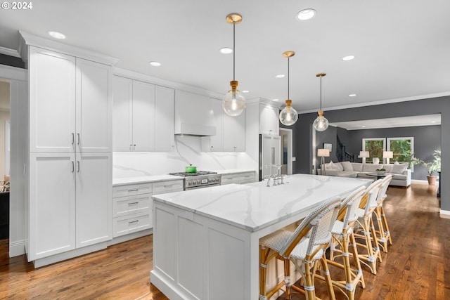 kitchen featuring hanging light fixtures, a center island with sink, and white cabinets