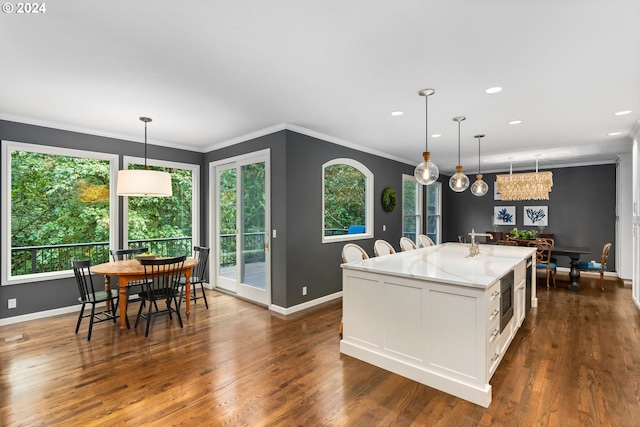 kitchen featuring white cabinetry, light stone countertops, an island with sink, dark hardwood / wood-style flooring, and decorative light fixtures