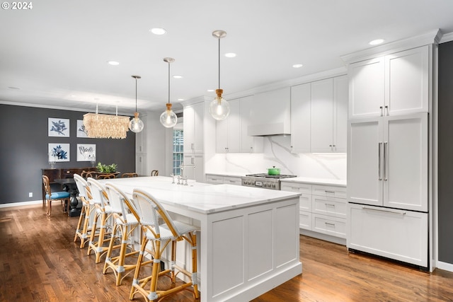 kitchen featuring hanging light fixtures, white cabinetry, light stone countertops, and a kitchen island with sink