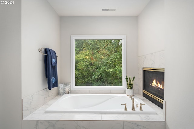 bathroom featuring a premium fireplace and tiled bath