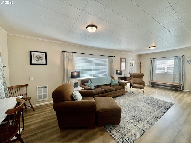 living room with heating unit, crown molding, baseboards, and wood finished floors