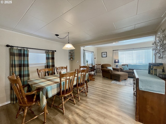 dining space featuring ornamental molding and light wood finished floors