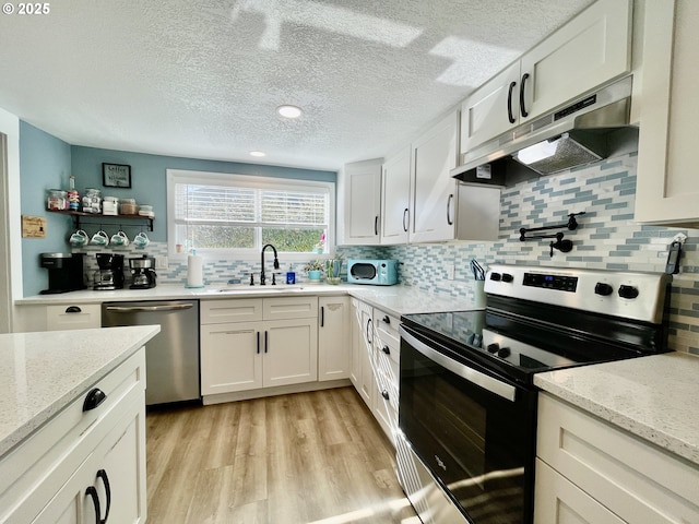 kitchen with stainless steel appliances, white cabinets, a sink, and under cabinet range hood