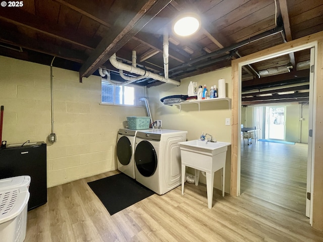 laundry room with laundry area, light wood-type flooring, independent washer and dryer, and concrete block wall