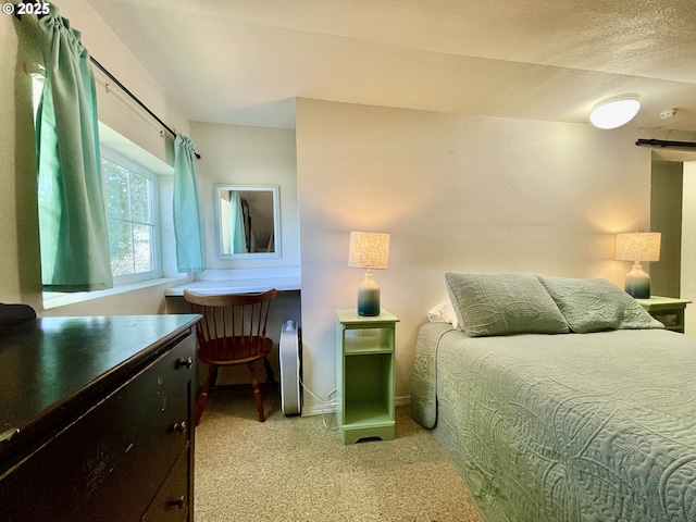 bedroom featuring light colored carpet, a textured ceiling, and baseboards