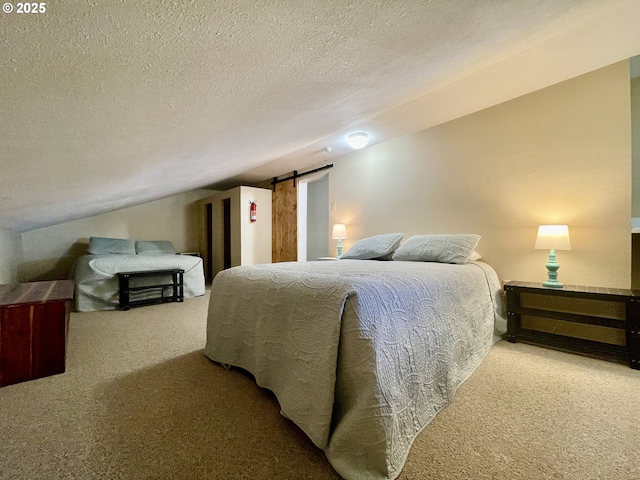 bedroom with a textured ceiling, a barn door, carpet, and lofted ceiling