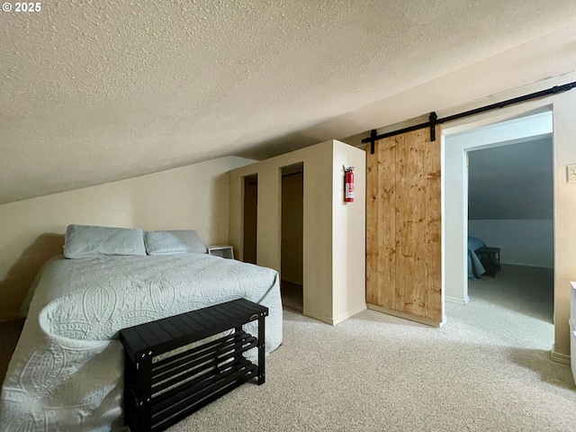 bedroom featuring a barn door, a textured ceiling, and light colored carpet