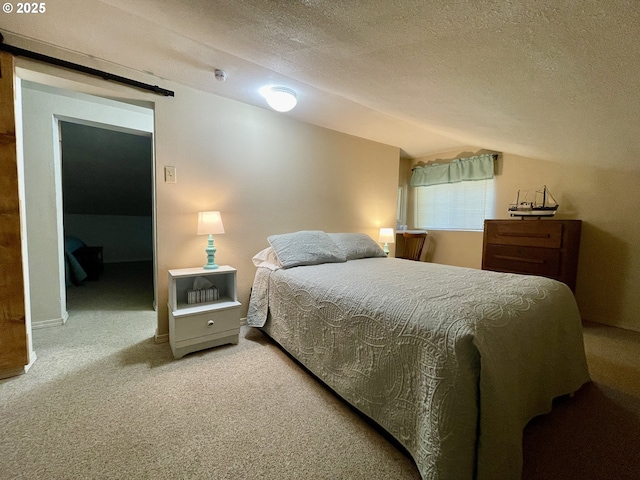 carpeted bedroom with lofted ceiling, a textured ceiling, and a barn door