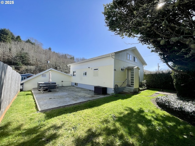 back of property featuring entry steps, a patio, fence, and a lawn