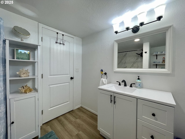 full bath with a shower, a textured ceiling, vanity, and wood finished floors