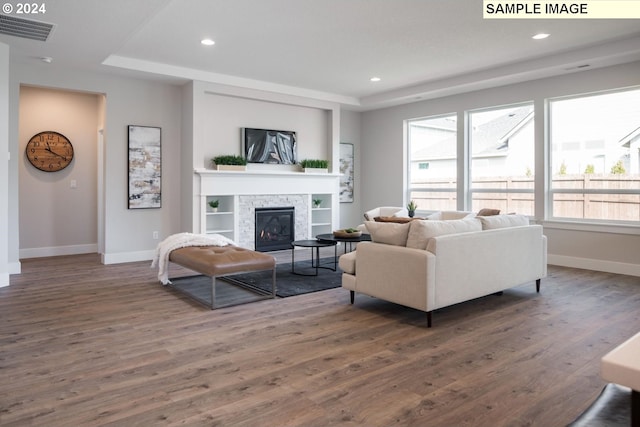 living room featuring a fireplace, dark wood-type flooring, and a tray ceiling