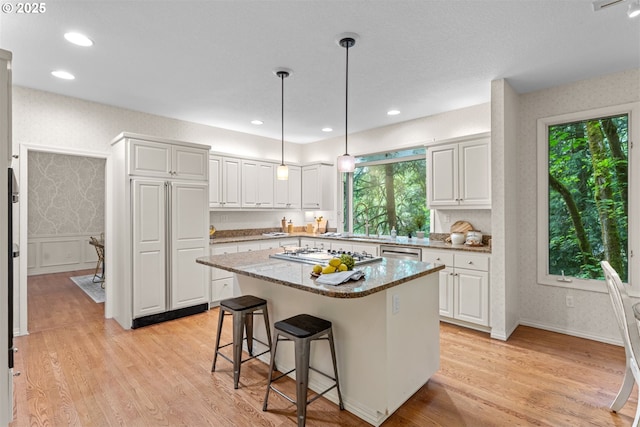 1739 Palisades Terrace Dr, Lake Oswego, OR 97034 - kitchen featuring appliances with stainless steel finishes, white cabinets, light wood-style flooring, a kitchen island, and a breakfast bar area