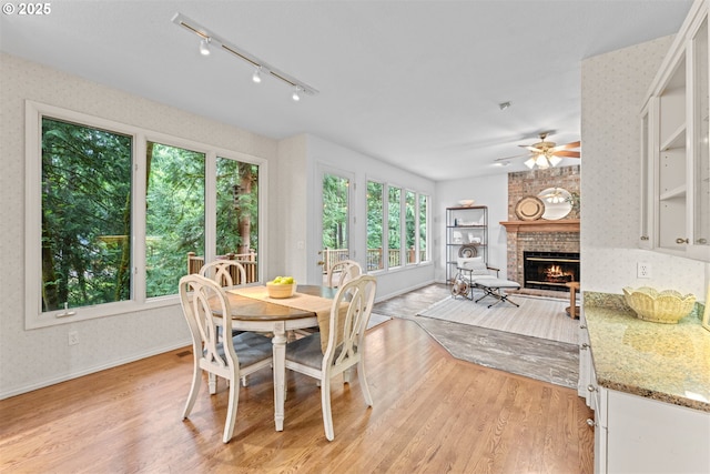 1739 Palisades Terrace Dr, Lake Oswego, OR 97034 - dining room featuring ceiling fan, a brick fireplace, light wood-style floors, track lighting, and baseboards