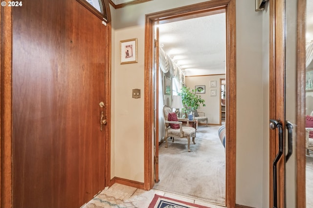 foyer with light carpet and crown molding