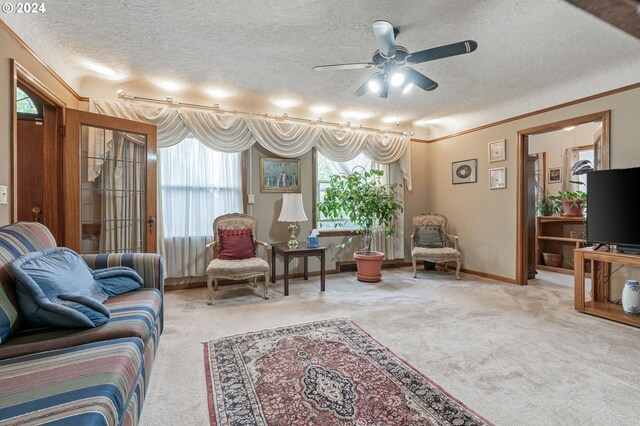 living room featuring ceiling fan, light colored carpet, crown molding, and a textured ceiling