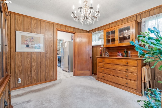 carpeted bedroom featuring stainless steel refrigerator, wooden walls, a chandelier, and a textured ceiling