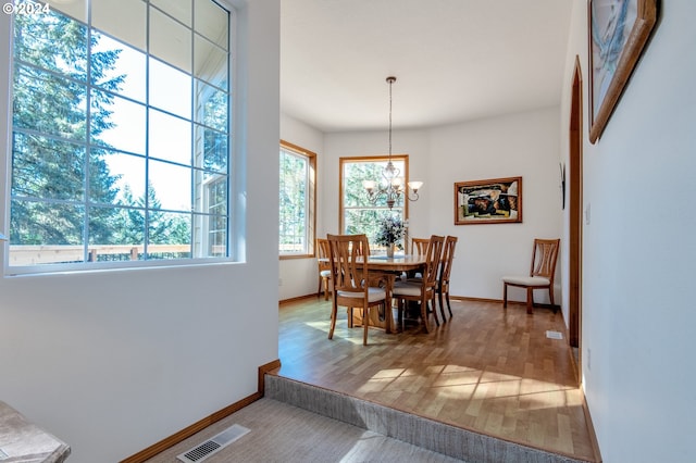 dining space with wood-type flooring and an inviting chandelier