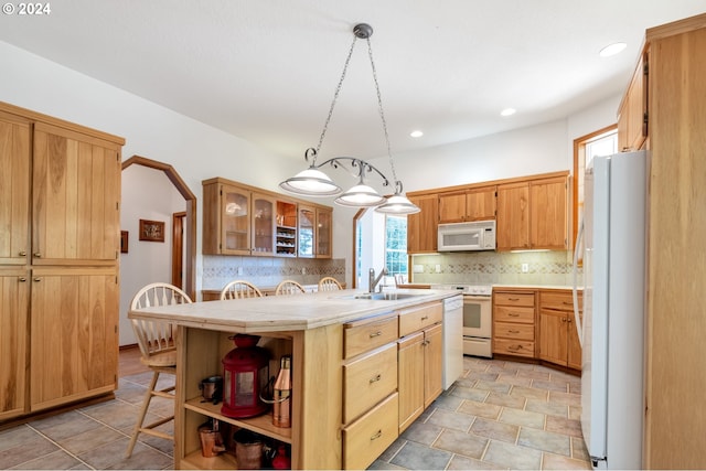 kitchen with a center island with sink, decorative light fixtures, sink, and white appliances