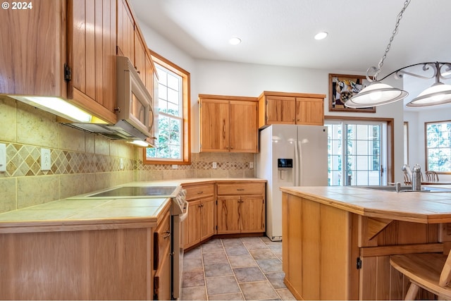 kitchen featuring backsplash, white appliances, light tile patterned floors, tile countertops, and sink