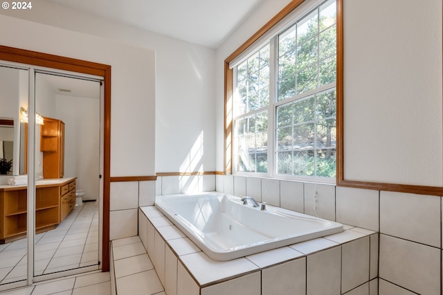 bathroom featuring tiled tub, vanity, tile patterned floors, and a wealth of natural light