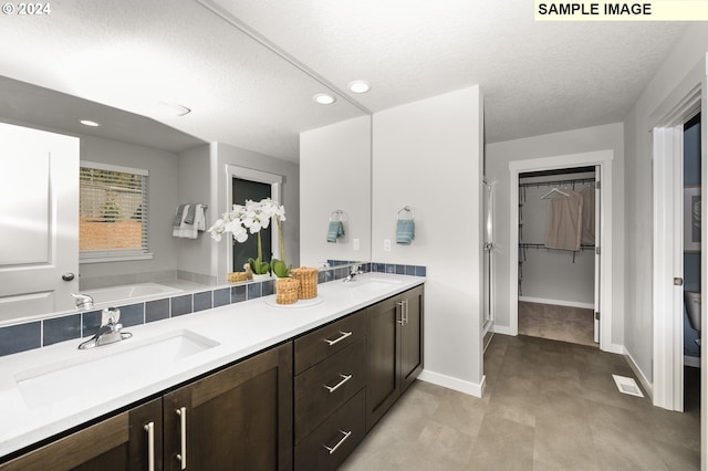 bathroom with a washtub, vanity, and a textured ceiling