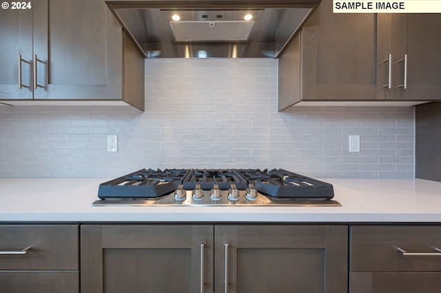 kitchen with wall chimney exhaust hood, decorative backsplash, and stainless steel gas stovetop