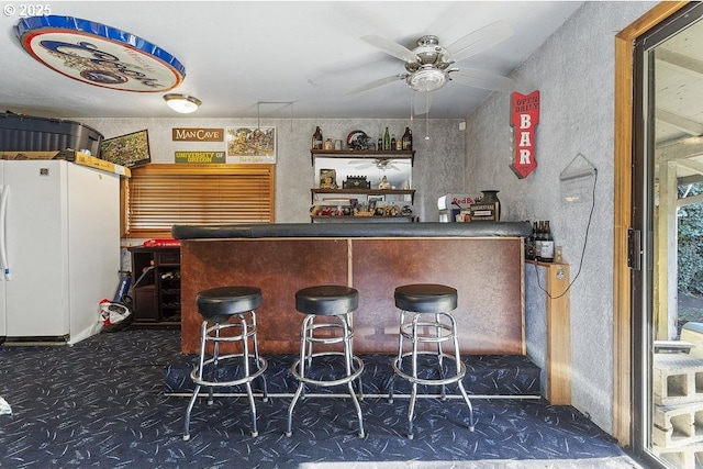 bar with ceiling fan and white refrigerator