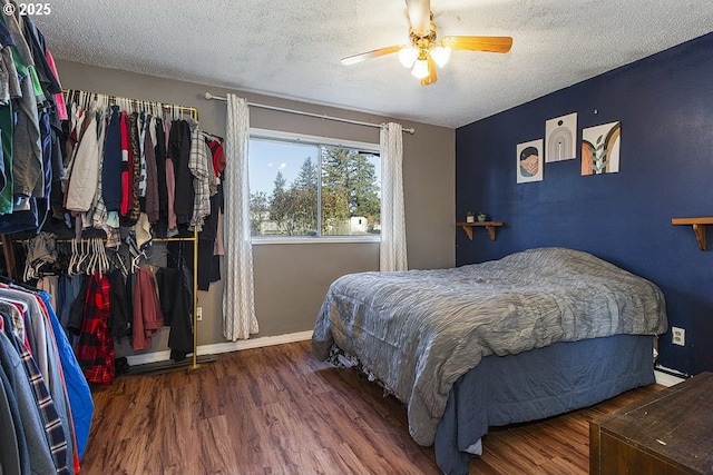 bedroom featuring ceiling fan, dark hardwood / wood-style floors, and a textured ceiling