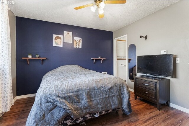 bedroom with a textured ceiling, ceiling fan, and dark hardwood / wood-style floors