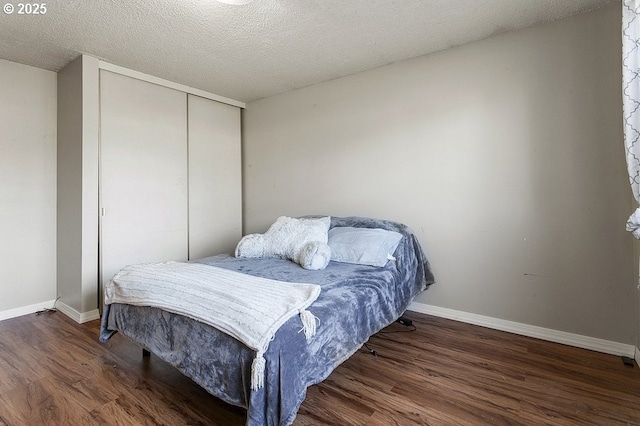 bedroom with a textured ceiling, dark hardwood / wood-style flooring, and a closet