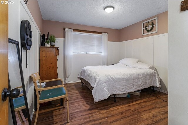 bedroom with dark hardwood / wood-style floors and a textured ceiling