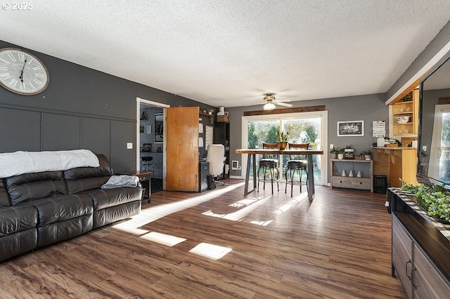 living room featuring ceiling fan, dark hardwood / wood-style flooring, and a textured ceiling