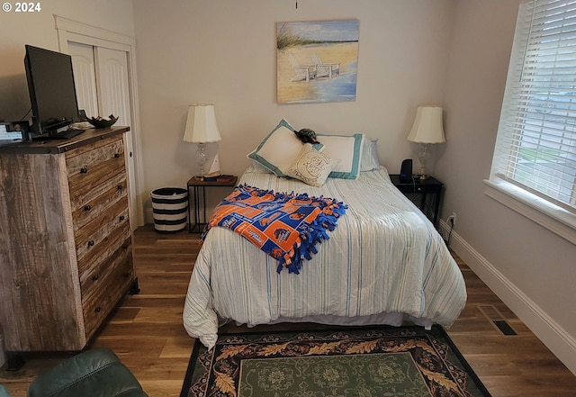 bedroom with dark wood-type flooring and a closet