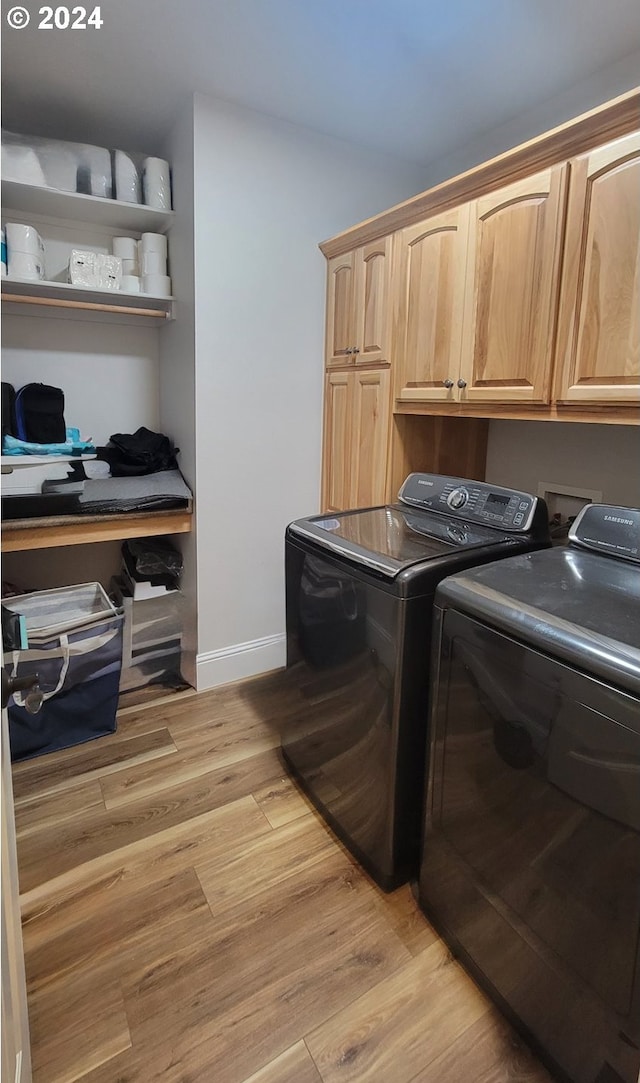 laundry room with washer and dryer, cabinets, and light wood-type flooring