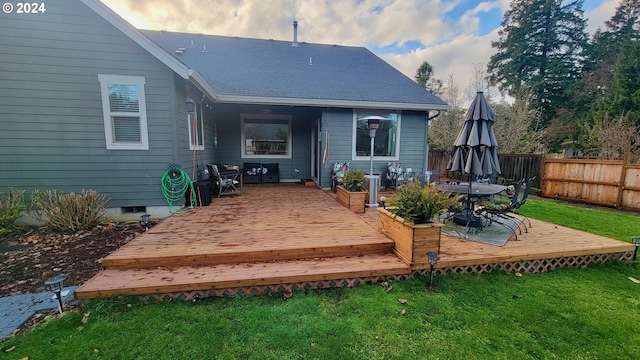 rear view of house featuring a lawn and a deck