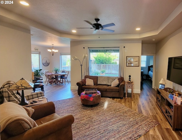 living room featuring a textured ceiling, light hardwood / wood-style floors, and ceiling fan with notable chandelier