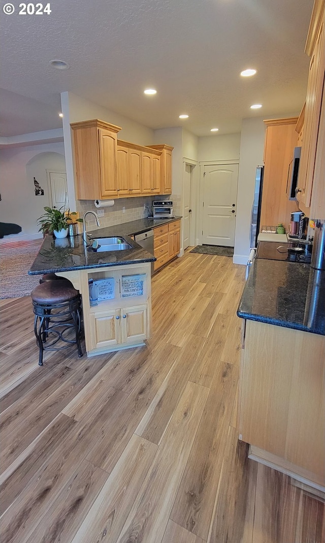 kitchen with sink, kitchen peninsula, light hardwood / wood-style floors, light brown cabinetry, and appliances with stainless steel finishes