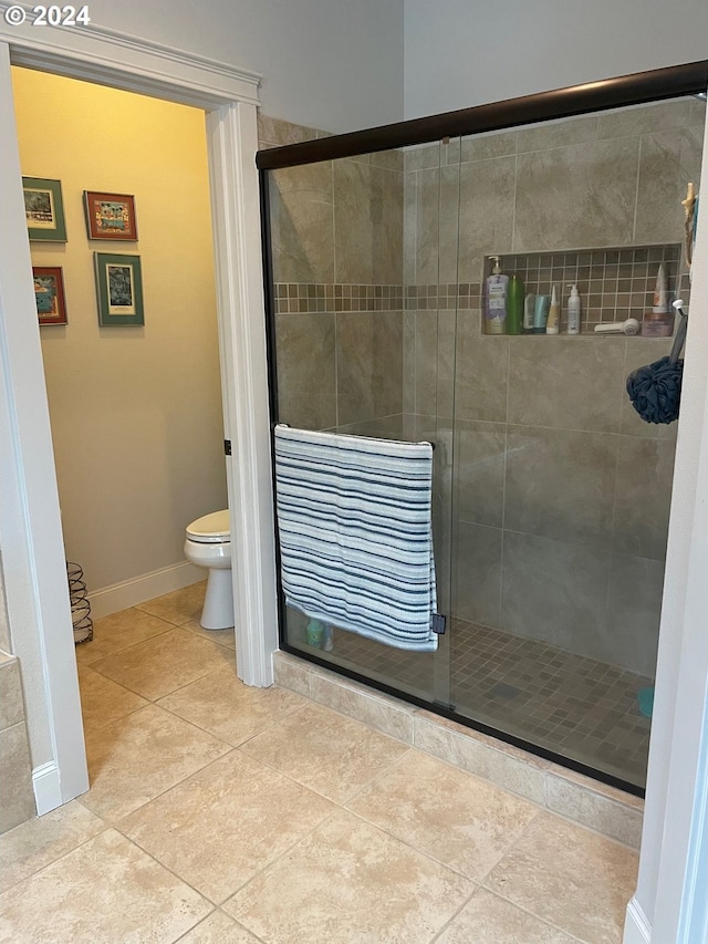 bathroom with tile patterned floors, a shower with shower door, and toilet