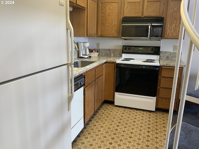 kitchen featuring a sink, white appliances, brown cabinetry, and light floors