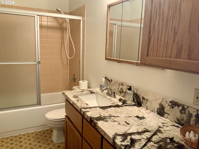 full bathroom featuring combined bath / shower with glass door, vanity, toilet, and tile patterned floors