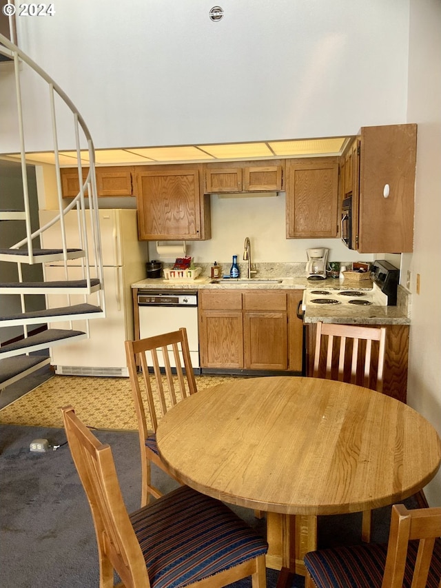 kitchen featuring brown cabinetry, white appliances, light countertops, and a sink