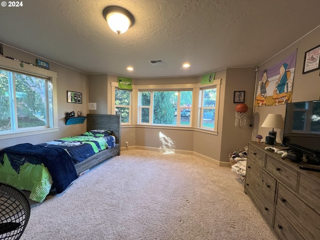 carpeted bedroom featuring a textured ceiling and multiple windows