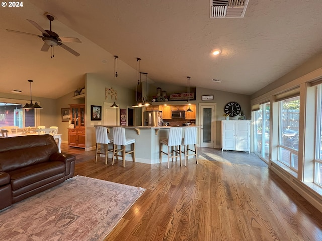 living room featuring hardwood / wood-style flooring, ceiling fan, and lofted ceiling