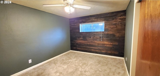 carpeted spare room featuring ceiling fan and wooden walls